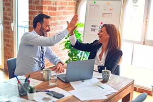 A small business owner and outsourced accountant sat at a desk and high-fiving