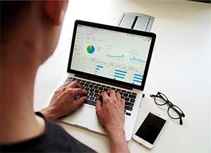 Overhead shot of a man typing on a computer with a screen displaying accounting charts and graphs